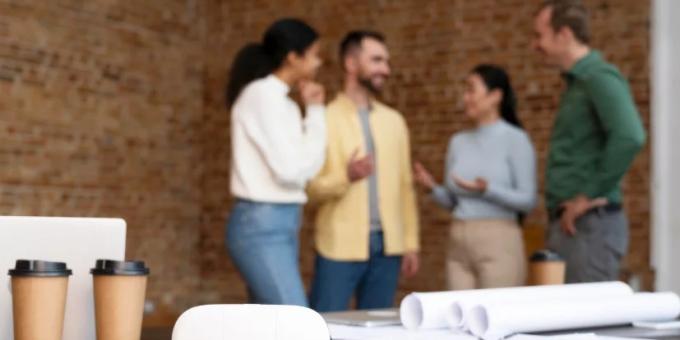Equipo de trabajo conversando en un entorno colaborativo durante una reunión informal en la oficina