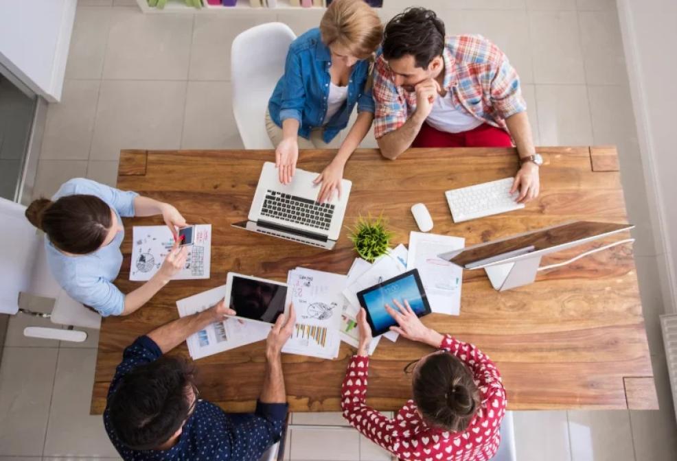Equipo multidisciplinar trabajando en una mesa con portátiles y documentos en un entorno colaborativo de oficina